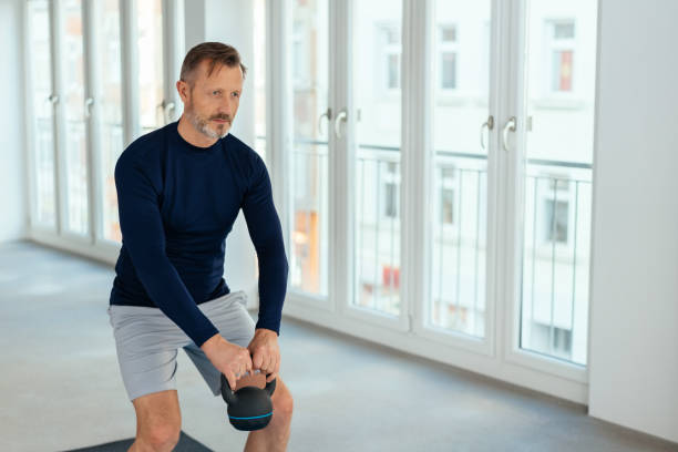 istock Fit middle-aged man lifting a kettle weight 1248749748