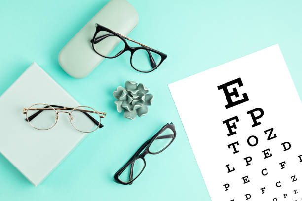 istock Collection of eyeglasses with eye test table. Optical store, glasses selection, eye test, vision examination at optician, fashion accessories concept. Top view 1248750452