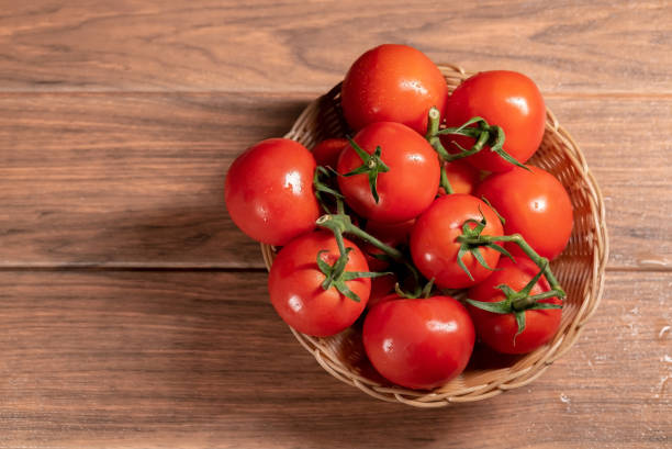 istock Organic red tomatoes with green stems in a brown woven basket 1248751472