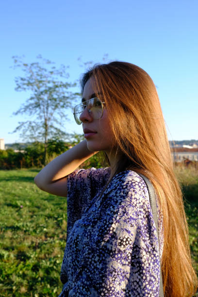Young and attractive girl with long brown hair and summer dress in the park at golden hour
