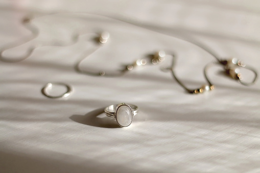 Silver jewelry on white background, illuminated by sunlight. Selective focus.