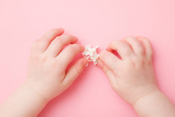 Close up view of beautiful little girl hands with gentle manicure nails, pink gel polish, hearts design