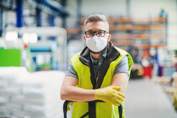 istock Man worker with protective mask standing in industrial factory or warehouse. 1248760685