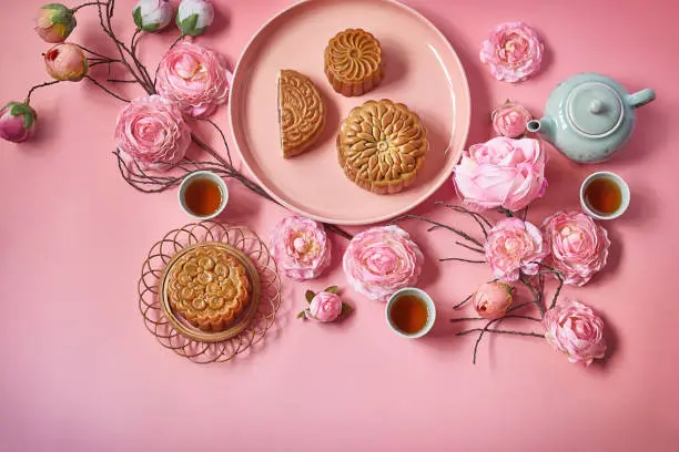 Moon cake decorated with pink flower with teapot and cup of tea.