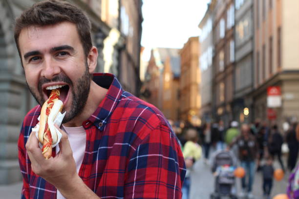 istock Young man eating a hot dog outdoors 1248761663
