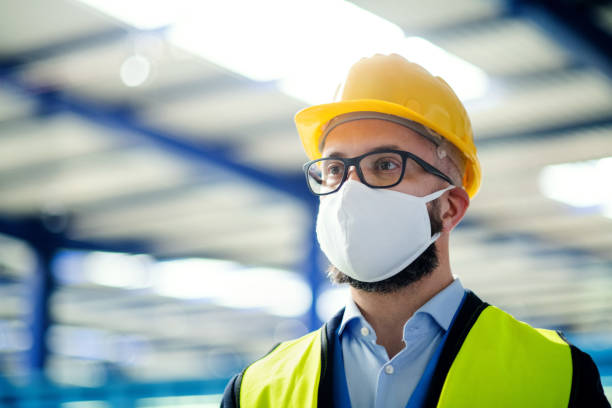 istock Technician or engineer with protective mask and helmet standing in industrial factory. 1248761687