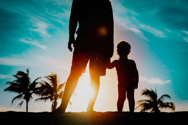 istock father and little daughter holding hands at sunset beach 1248762275