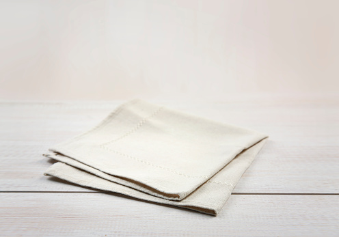 Soft beige folded kitchen towel on wooden table.Burlap cloth empty space.Food advertisement backdrop.