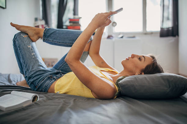 istock Beautiful woman using smart phone in bed 1248765115