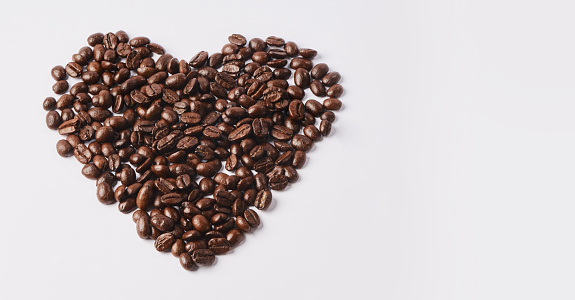 Studio shot of coffee beans shaped in a heart against a white background