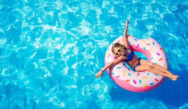 niño divertido en donut inflable en la piscina - floatation device fotografías e imágenes de stock