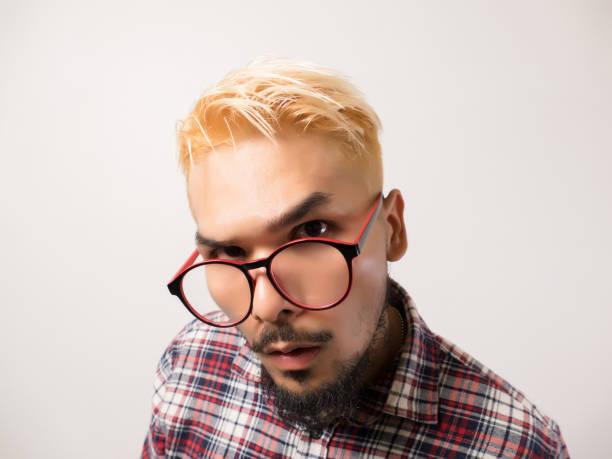 Closeup photo of young pensive guy wearing orange sweater touching glasses serious trying optics isolated on purple color background.