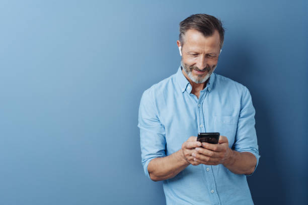 istock Man wearing audio ear buds holding a mobile phone 1248768638