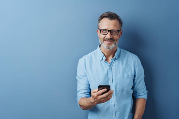 Smiling friendly man holding his mobile phone stock photo