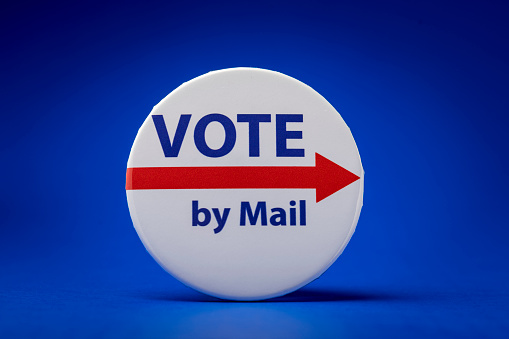 Photograph of electing button and envelopes for vote by mail concept.