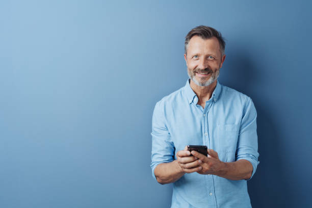 istock Happy relaxed man holding his mobile phone 1248769547