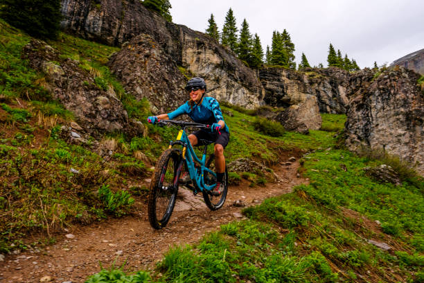 istock Female mountain biker rides down dirt path 1248771924