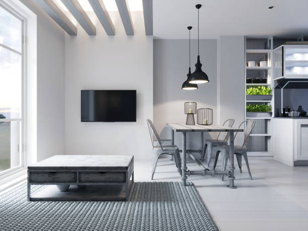 istock Modern area with a TV in a studio apartment with a loft style kitchen in white color. Designer dining table, modern kitchen and sofa with ottoman. 1248772699