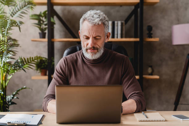 istock Mature man working on laptop while sitting at his working place 1248775615