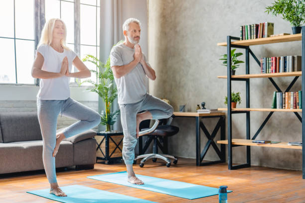 istock Senior couple performing tree pose on yoga mats at home while practicing 1248775853