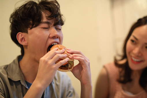 Portrait of asian man eating burger