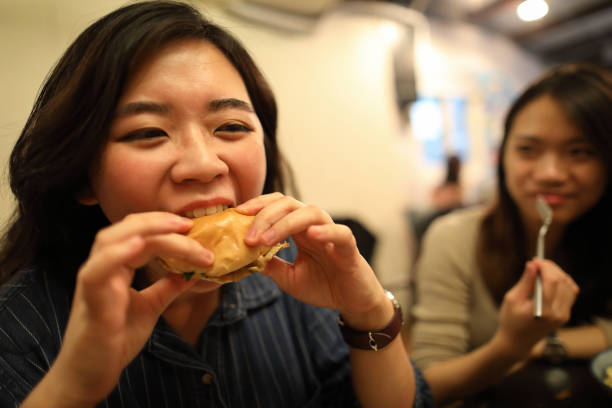 istock Asian woman eating burger closeup 1248778036