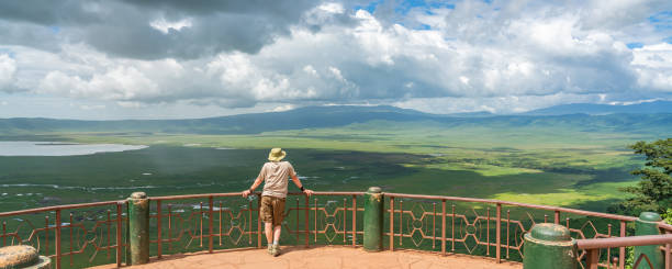 ein mann blickt in den ngorongoro crater national park mit dem magadisee - wildlife tracking tag stock-fotos und bilder