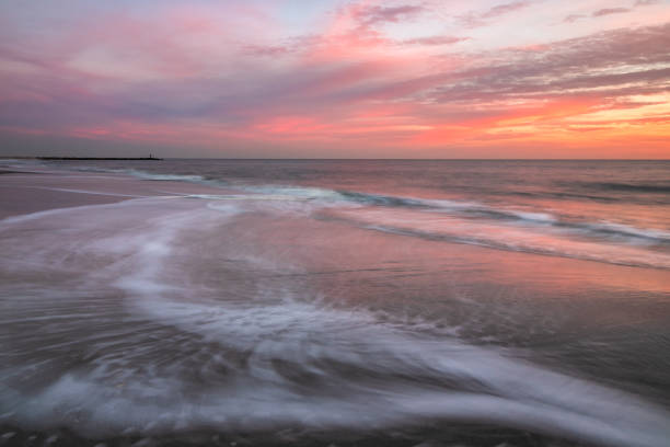 istock Waves retreating back into the sea under a vibrant pink and orange sky. 1248779589