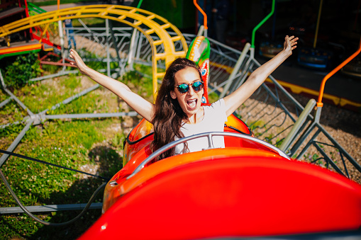 Happy kids having fun in an amusement park riding on a rollercoaster and screaming - lifestyle concepts