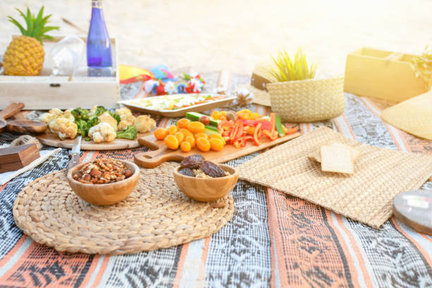 Beautiful summer picnic on the beach at sunset in zero waste style. Eco friendly idea for weekend staycations Beautiful summer picnic on the beach at sunset in zero waste style. Organic fresh fruit, cheese and vegetables on linen blanket. Eco friendly idea for weekend staycations. staycation photos stock pictures, royalty-free photos & images