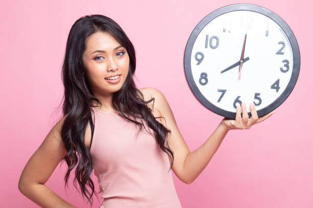 istock Young Asian woman with a clock. 1248782280