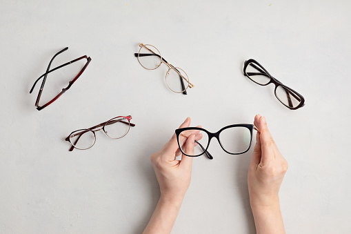 Mujer sosteniendo anteojos. Tienda óptica, selección de gafas, prueba de ojos, examen de visión en óptica, concepto de accesorios de moda. Vista superior photo