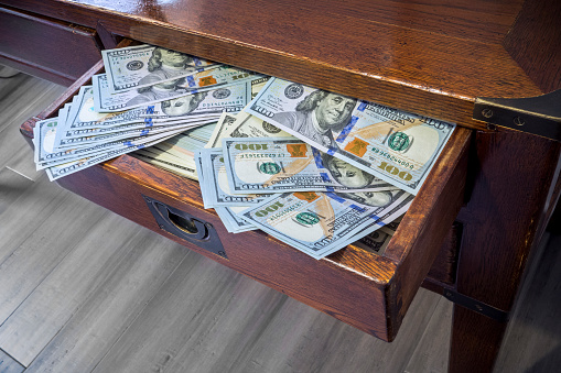 Looking down on wooden desk with 100 dollar bills