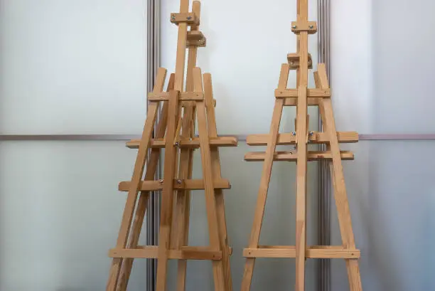 4 wooden easels at glass wall in modern building. Equipment for drawing or painting classes.