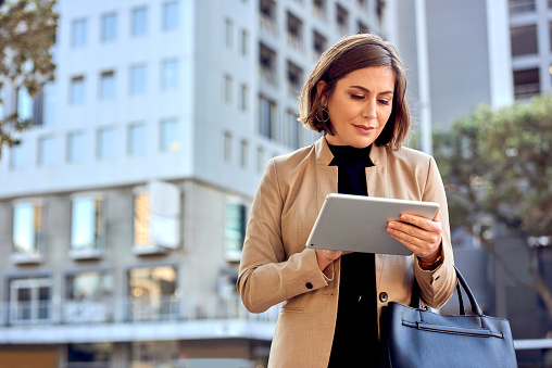 Cropped shot of a businesswoman using a digital tablet while out in the city