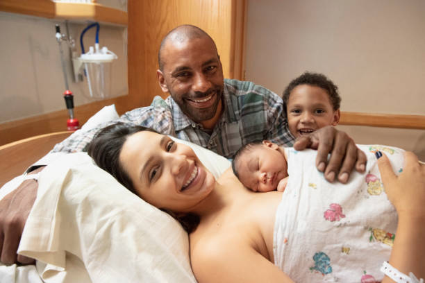 Mixed race family admiring their newborn baby at hospital with mother stock photo