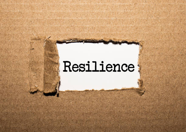 The text resilience. behind torn brown paper
