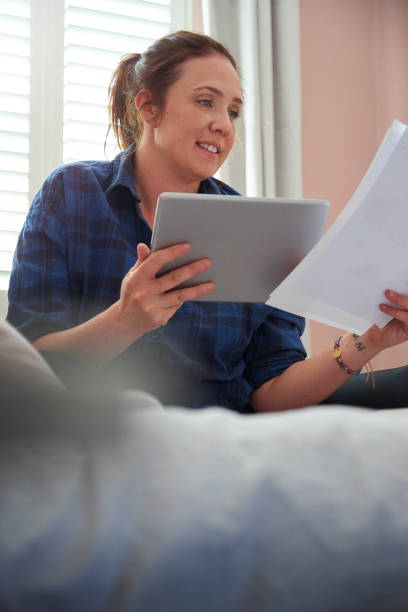 istock Young woman sat on her bed smiling reading through paperwork 1248797179
