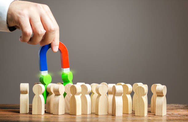 istock A hand with a magnet pulls green people out of crowd. Recruiting new workers, headhunters. Search for talented workers. Choose a candidate for work, competition for post. Promising specialists. 1248799935