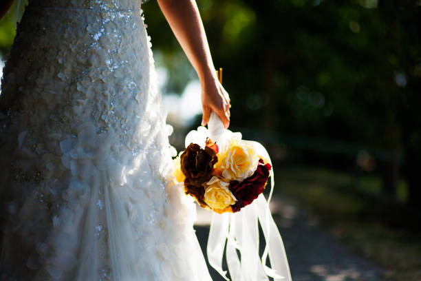 istock Bride Holding Yellow and Dark Red Roses Under Sunlight 1248800474