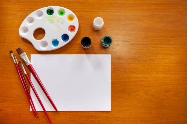 Artistic set with brush, paper, paint and palette on a wooden background. art, creativity and people concept. top view and copy space