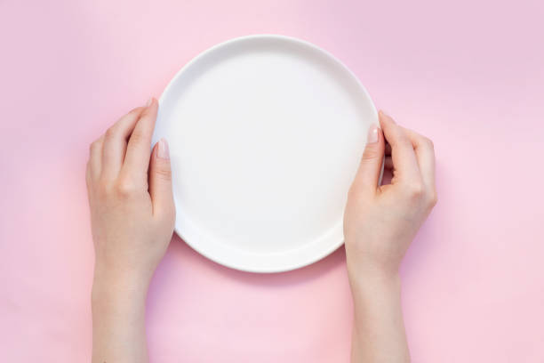 istock Woman with empty plate on pink background, top view 1248800692