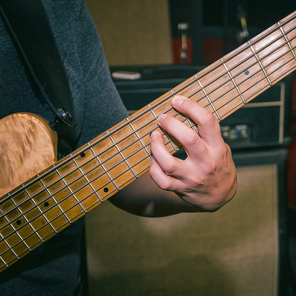The bass player plays a five-string bass guitar close-up. Plays bass guitar. Selective focus