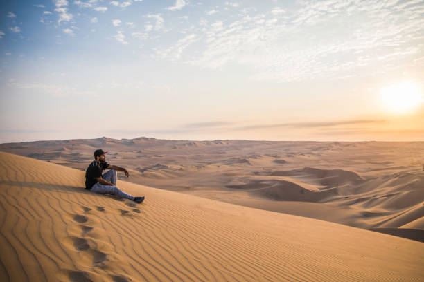 istock man sitting on a top of a dune 1248805546