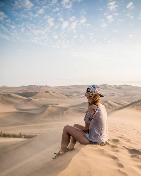 istock woman sitting on a top of a dune 1248805562