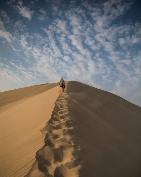 砂漠で砂丘を登る女性 - desert landscape morocco sand dune ストックフォトと画像
