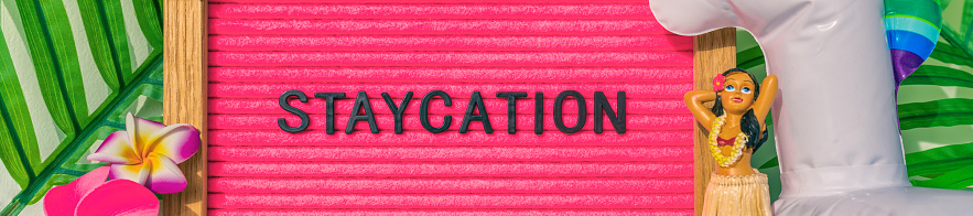 Staycation banner sign for summer vacation plans during COVID-19. Funny pink felt board text for staying home for the holidays. What to do this summer without traveling.