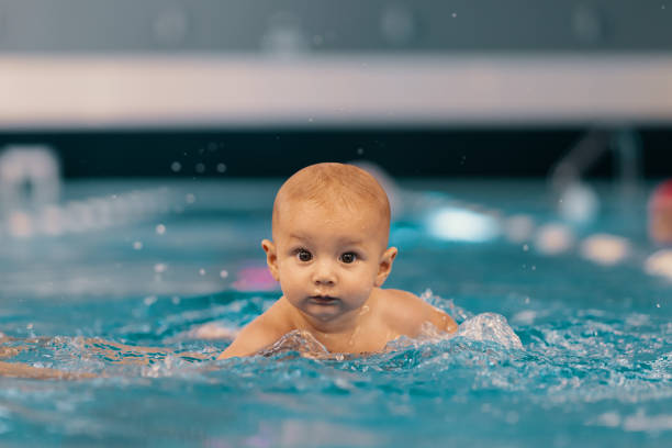 istock Mother and little son having fun in a swimming pool 1248808936