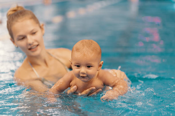 istock Mother and little son having fun in a swimming pool 1248808937