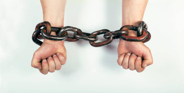 istock Hands clenched into fists in chains on a white background 1248810431
